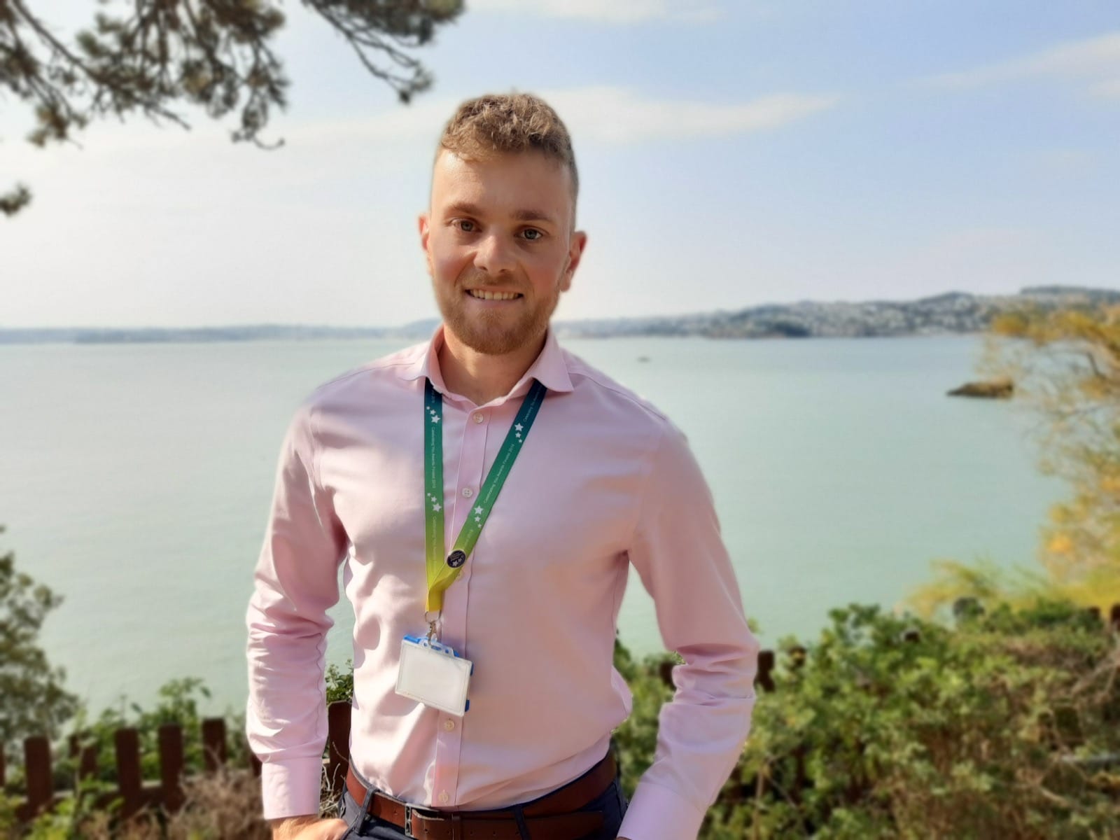 A photo of medicines optimisation pharmacist, Charlie, with the sea in the background