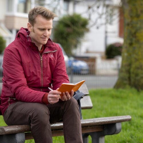 A man on a bench looking at a notebook