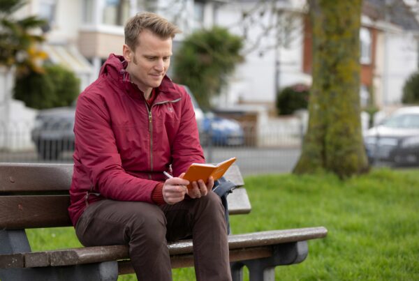 A man on a bench looking at a notebook