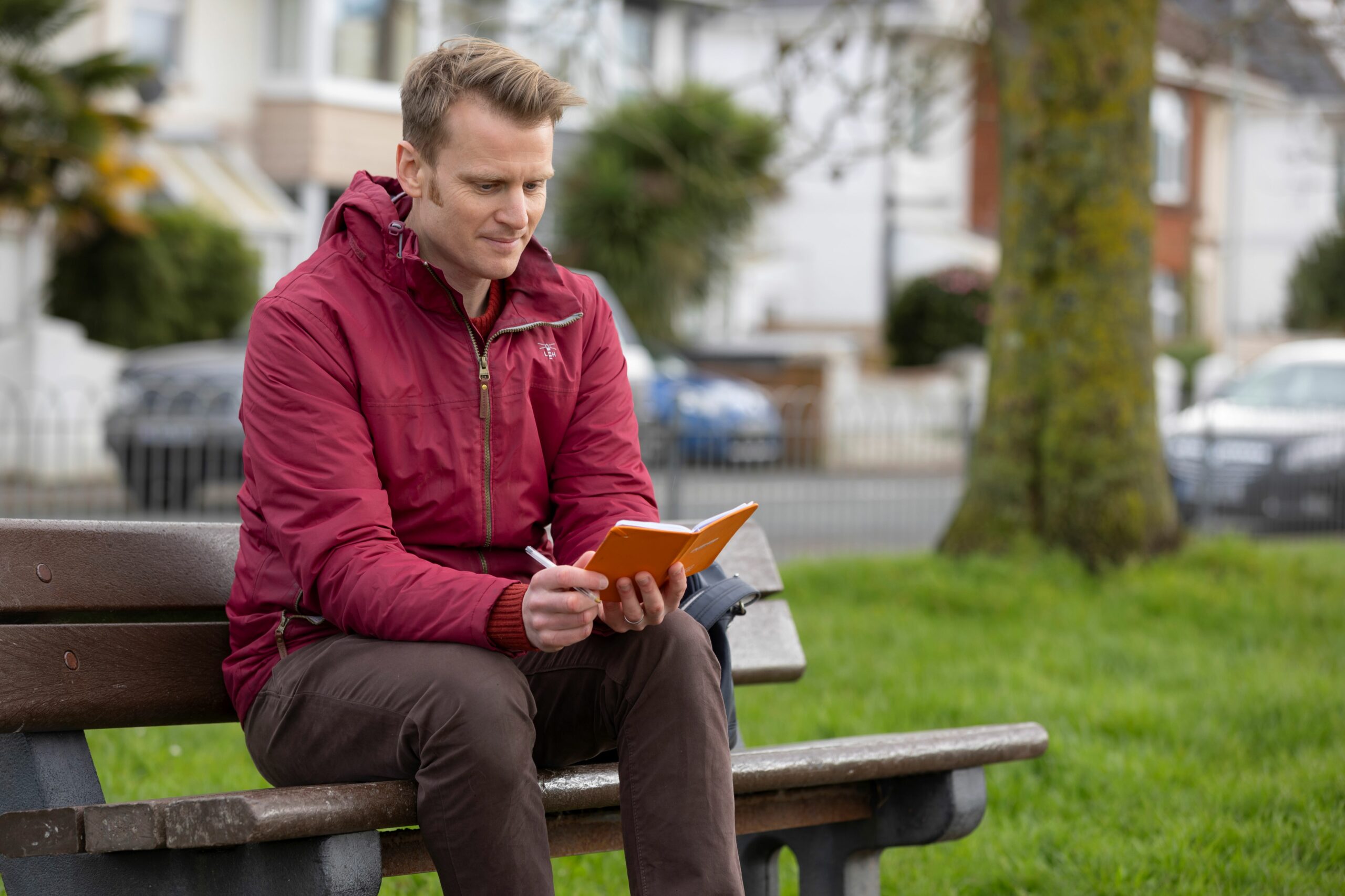 A man on a bench looking at a notebook