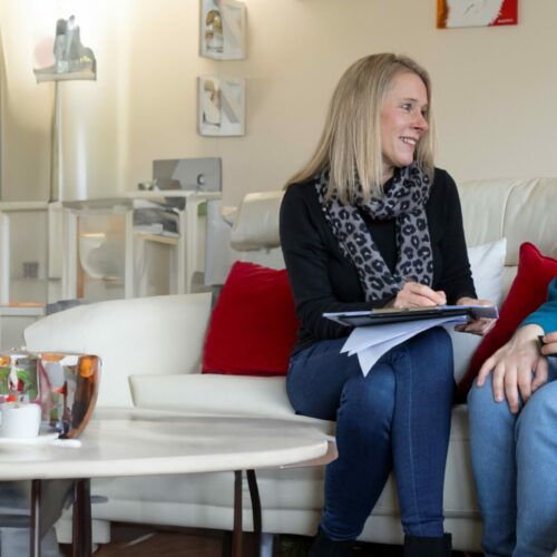 Two people sat on a sofa with a clip board