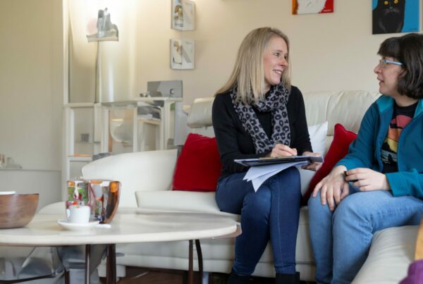 Two people sat on a sofa with a clip board