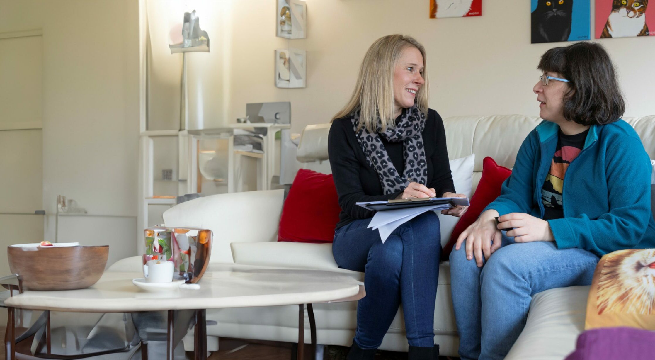 Two people sat on a sofa with a clip board