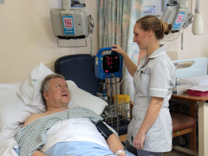 man in hospital bed with nurse checking