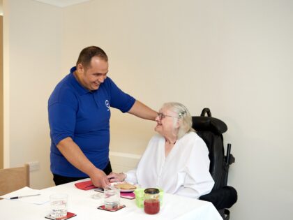 A social care worker with a older person to eat breakfast