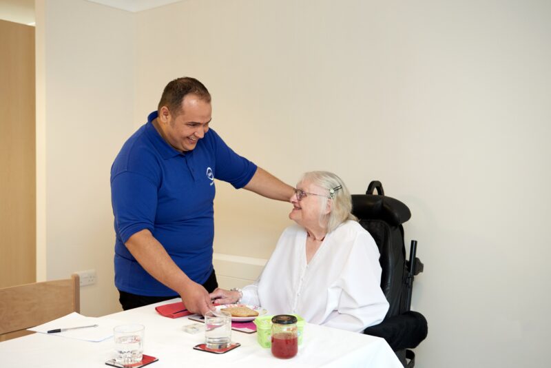 A social care worker with a older person to eat breakfast