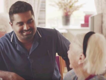 A male nurse smiling a a older resident in a care home