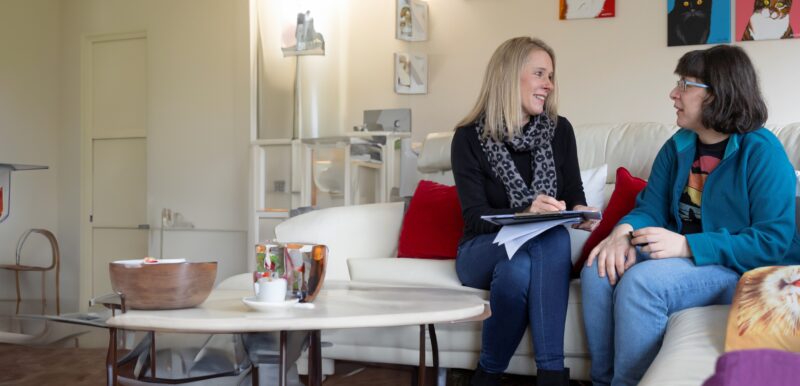 Two people sat on a sofa with a clip board