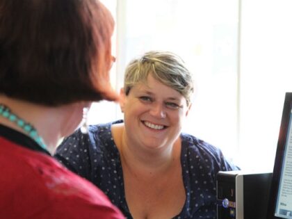 A women smiling supporting someone to use a computer